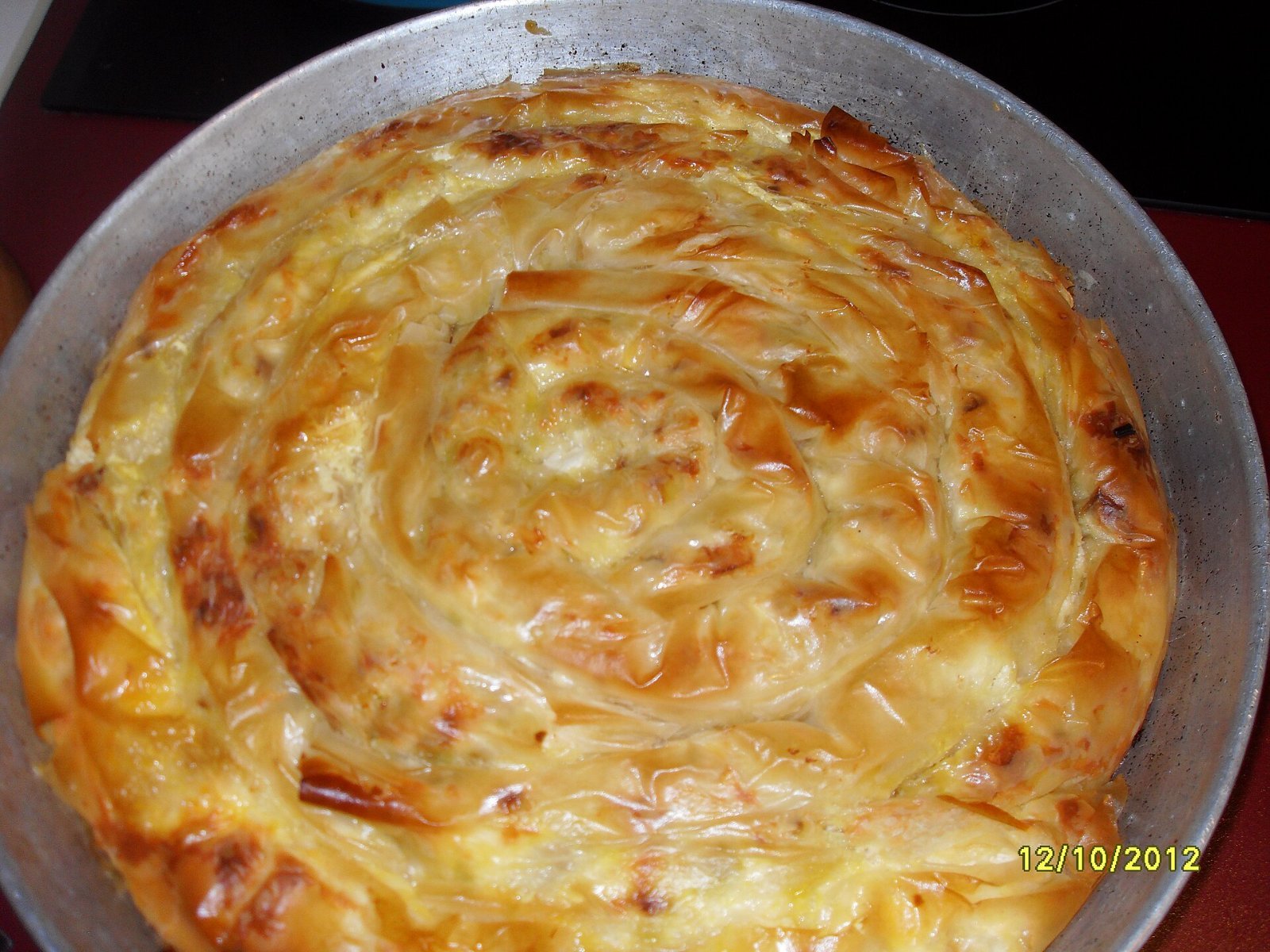 A round homemade banitsa with golden, flaky spiral layers of pastry